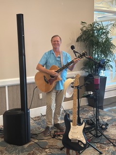 Michael McCormick set up for an indoor ballroom event with guitars and PA