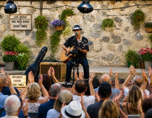 Michael McCormick singing and playing acoustic guitar as an outdoor audience claps along