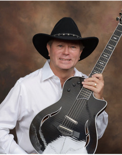 Michael McCormick in a black cowboy hat with an acoustic guitar