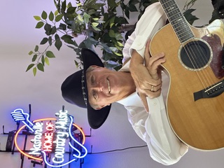 Michael McCormick in a black cowboy hat under a Nashville neon sign